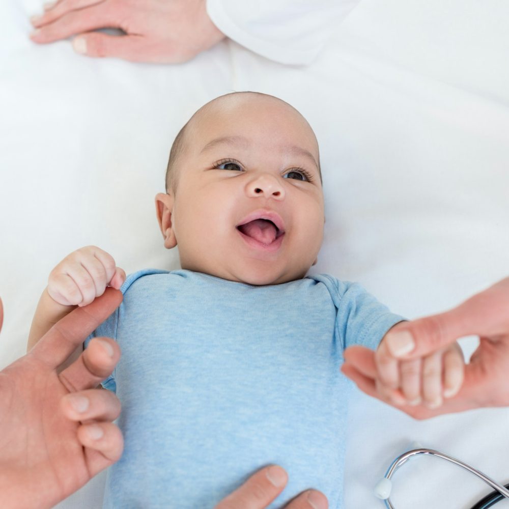 cropped shot of pediatricians taking care of adorable little baby on bed